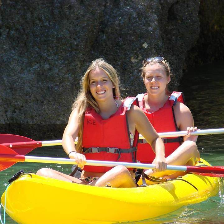 two girls smiling while on a kayak