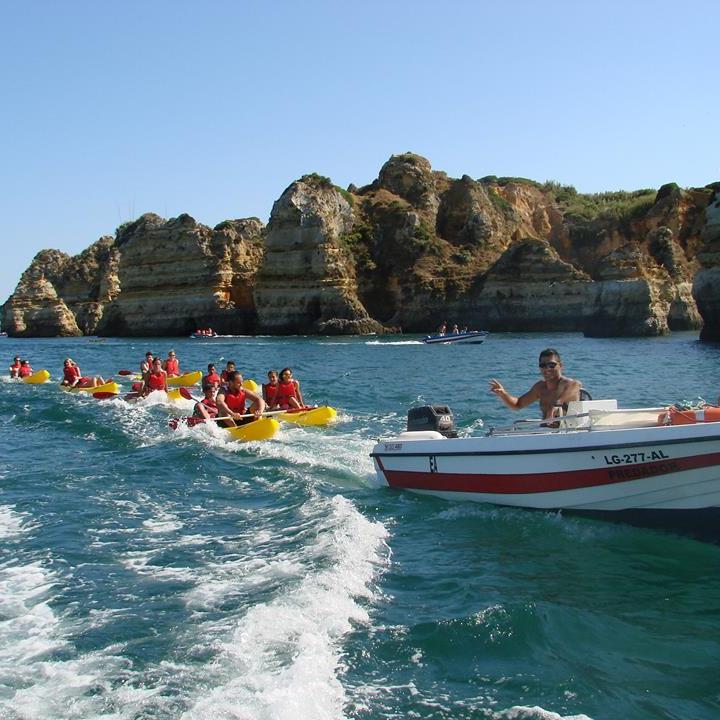 a boat pulling some kayaks in the sea