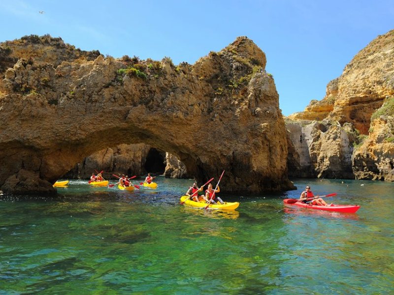 people kayaking under a cave