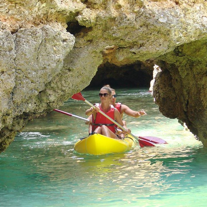 a couple kayaking under a cave
